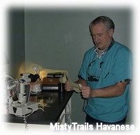 A man in blue scrubs is looking down at a sheet of paper that he is holding.