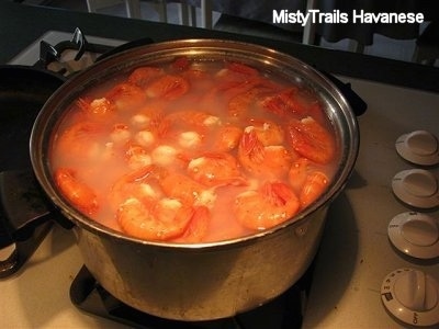 A pot of water with Prawns in it on a stove.