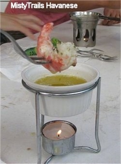 Close up - A Prawn is being dumped into butter on a fork.