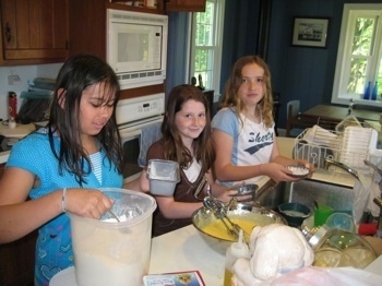 A Cake being prepared for Bruno the Boxer by three kids in a kitchen