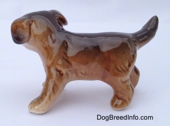 The left side of a brown and black porcelain Aussie puppy figurine. The figurine is very glossy.