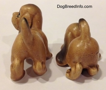 The back side of two Vintage miniature ceramic Bloodhound figurines. The back paws of the figurines are very detailed.