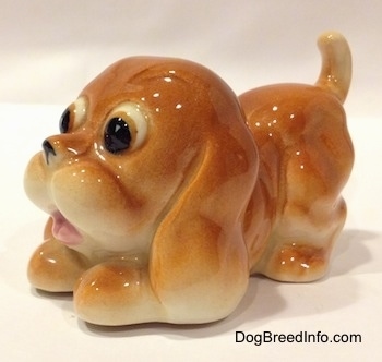 The front left side of a tan Cartoon style Bloodhound puppy figurine. The eyes of the figurine are big boldging eyes.