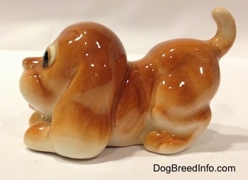 The left side of a tan Cartoon style Bloodhound puppy. The figurine has its mouth open and a tongue sticking out.