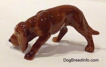The left side of a Hagen-Renaker miniature red variation of a Bloodhound figurine. The figurine has great paw details.