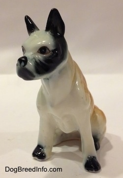 A red and white with black bone china Boxer figurine that is in a sitting pose. 