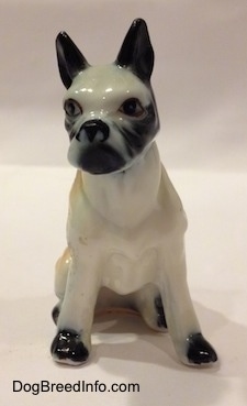 A red and white with black bone china Boxer figurine that is in a sitting pose. The figurine has black ears.