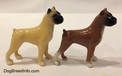The right side of two color variations of a miniature Boxer dog standing figurine. Both figurines have black muzzles.