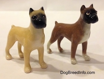 The front right side of two color variations of a miniature Boxer dog standing figurine. Both figurines have detailed eyes.