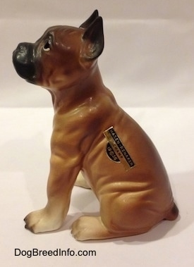 The left side of a brown with black and white Boxer puppy figurine. The figurine is highly detailed.