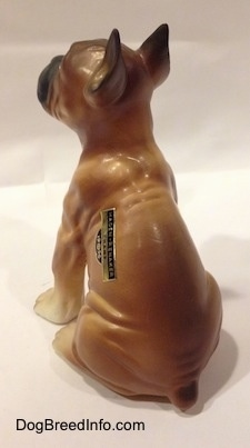 The back of a brown with black and white Boxer puppy figurine. The figurine has black ear tips.