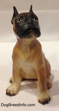 A brown with black and white Boxer puppy figurine. The figurine has a detailed face.