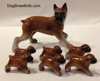 The right side of a brown with white and black Boxer mom with 6 puppies figurines. All of the figurines have black muzzles.