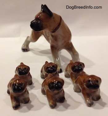 A brown with white and black Boxer mom with 6 puppies figurines. All the figurines have black circles for eyes.