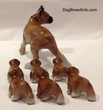 The back side of a brown with white and black Boxer mom with 6 puppies figurines. It is hard to differentiate the tails from the bodys of the figurines.