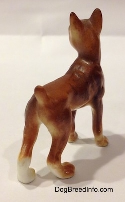 The back side of a bone china brown with white and black Boxer dog. The figurine has a short tail that is easily distinguishable from the body.