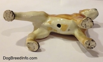 The underside of a brown with black and white ceramic Boxer dog figurine. There is a hole on the figurine.