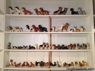 A collection of figurines on a white wall book shelf