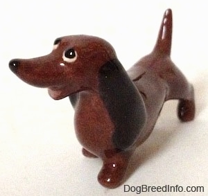 The front left side of a brown Dachshund figurine that is from 'Disney's Lady and the Tramp'. The figurine has a long nose and buldging eyes.
