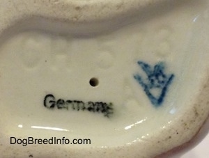 Close up - The underside of a Dachshund figurine. On the underside there are two stamps and an engraving. The stamps are Germany and the stamp of Goebel W.Germany. The engraving is of the letter/number combination - CH 573 A.
