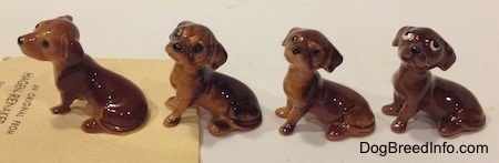 The left side of four different Dachshund Pup Seated figurines. The details in the figurines eyes vary.
