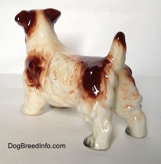 The back left side of a white with brown Lucas Terrier figurine. The figurine has its short tail in the air.