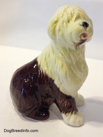 The right side of a brown with white porcelain Old English Sheepdog figurine. The mouth of the figurine is open.