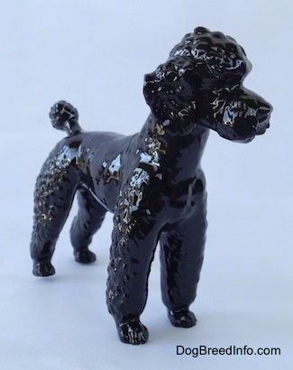 The front right side of a black Poodle standing figurine. Its hard to differentiate the ears from the body of the figurine.