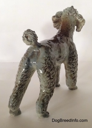 The back right side of a black, gray and brown Poodle figurine. The figurine has fine hair details.
