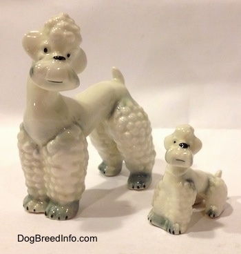 The front left side of two white with spots of gray Poodle figurines. The figurines have small black eye dots.