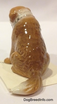 The back of a brown with white Saint Bernard figurine. The figurine has a long tail.