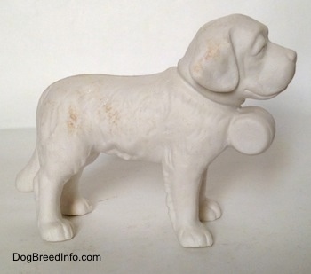 The right side of a figurine of a porcelain white bisque Saint Bernard. The figurine has fine hair details.