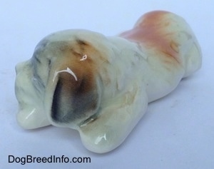 The front left side figurine of a Saint bernard puppy in a lying position. The figurine has short legs.