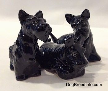 The front right side of a figurine of a black Scottish Terrier trio. The figurines are glossy.