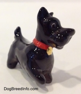 The front right side of a black figurine of a Scottish Terrier. The figurine has black circles for eyes.