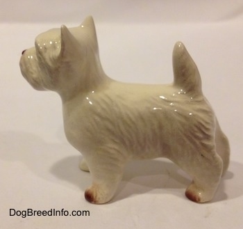 The left side of a white with tan figurine of a West Highland Terrier. The figurine is glossy.