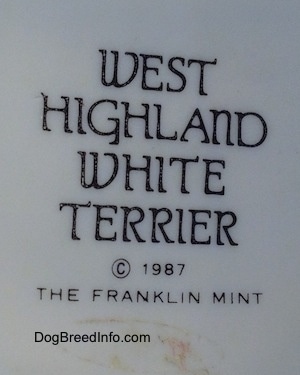 The underside of a West Highland Terrier White figurine. The figurine has a black stamp that reads 'West Highland White Terrier ©1987 The Franklin Mint'.