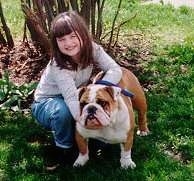 English Bulldog in the yard with her owner kneeling down holding onto her