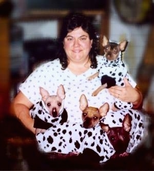 A lady is holding four Xoloitzcuintli puppies that are dressed as Dalmatians.