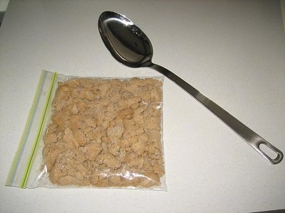 Crushed Milk Bones in a plastic ziplock bag next to a large spoon