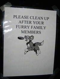 A sign with a dog jumping for a frisbee that says 'PLEASE CLEAN UP AFTER YOUR FURRY FAMILY MEMBERS