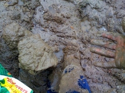A person's muddy foot and hand
