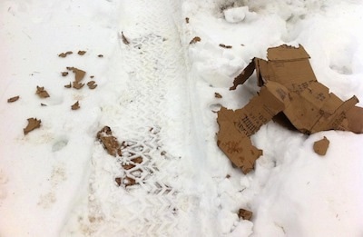 A ripped cardboard box that is in snow.