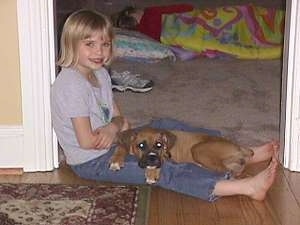 Amie sitting on the floor in a doorway with Allie the Boxer laying on her lap