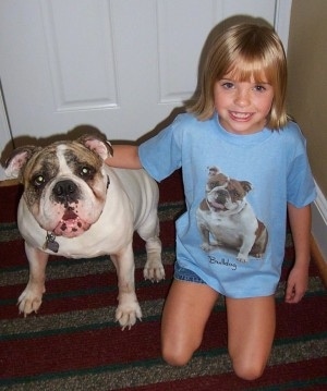 Spike the Bulldog sitting in front of a door next to Amie who is wearing a bulldog shirt