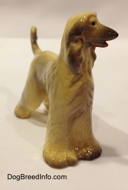 The front right side of a tan with black Retired Hagen-Renaker Afghan Hound with a long pointy snout shorter hair on its face and long ears that hang down to the sides.
