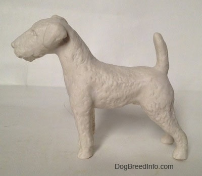 The left side of a white bisque porcelain Airedale Terrier dog figurine that is unglazed and not shiny.