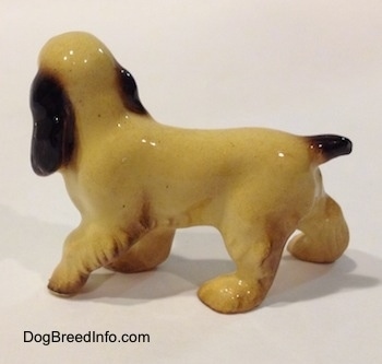 The left side of a tan with black and brown Cocker Spaniel ceramic figurine has light hair details.