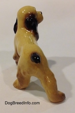The back of a tan with black and brown Cocker Spaniel ceramic figurine. It has a tail that is painted brown.