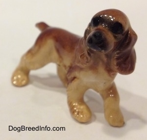 The front right side of a brown and tan ceramic Cocker Spaniel figurine. It has light hair brushings.